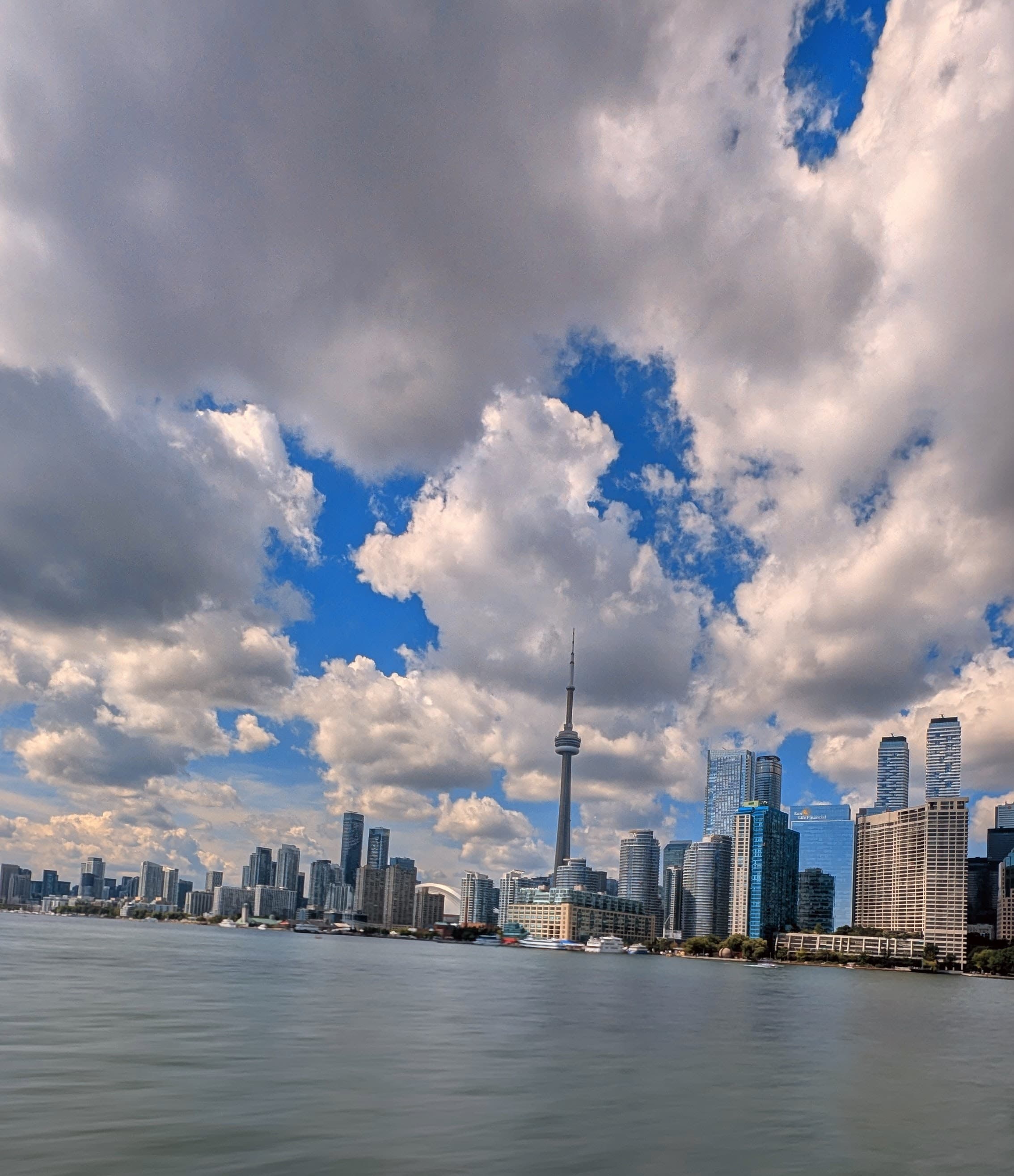 City skyline across open water under tall cumulus clouds